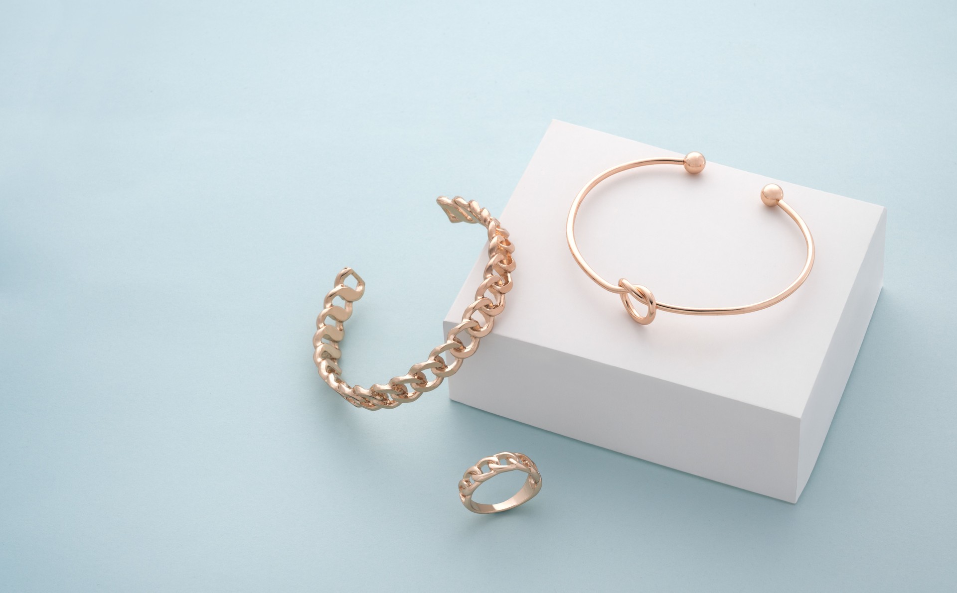 Modern golden bracelets and ring on white and blue background with copy space